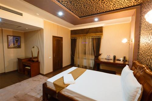 a bedroom with a large bed and a desk at Salut Hotel Almaty in Almaty