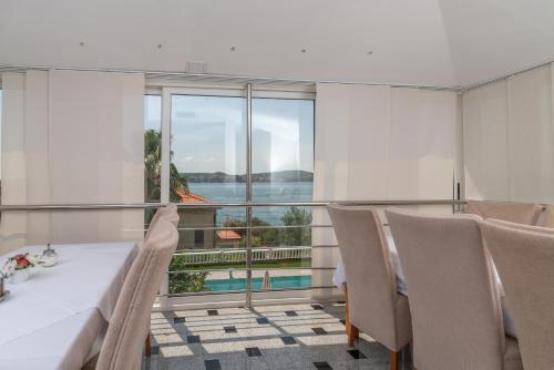 a dining room with a table and chairs and a large window at Villa Ana Trogir in Trogir