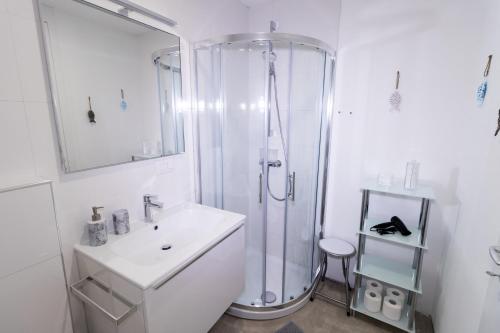 a white bathroom with a shower and a sink at Apartments Bella Tara in Piran