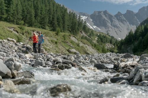 two people standing on a river with rocks at Chalet Silvretta Hotel & Spa in Samnaun