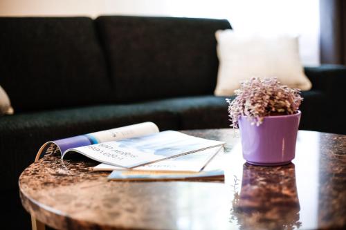 a coffee table with a book and a plant on it at Dönhoff Residence in Pärnu