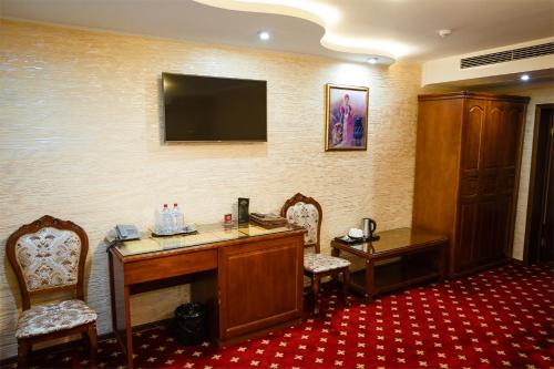 a hotel room with a desk and a television on the wall at Salut Hotel Almaty in Almaty