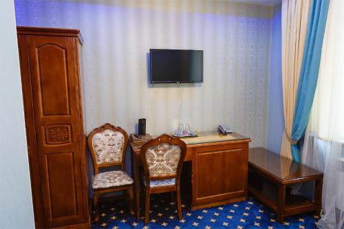 a room with a desk and two chairs and a television at Salut Hotel Almaty in Almaty