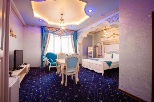 a hotel room with a bed and a table and chairs at Salut Hotel Almaty in Almaty