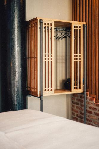 a wooden cabinet next to a bed in a room at 36 Phô Cô Hotel & Suites in Weimar