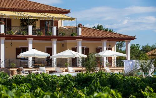 a building with tables and umbrellas in front of it at Aneli Luxury Villas-Villa Anastasia in Ayios Kirikos