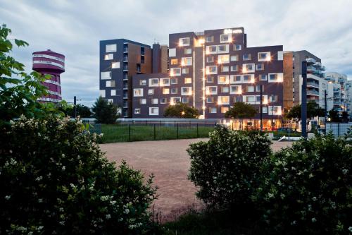 un grand bâtiment avec une tour d'horloge en face dans l'établissement ibis Lyon Carre De Soie, à Vaulx-en-Velin