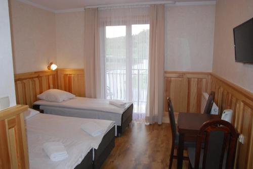 a room with two beds and a table and a window at Dom Wypoczynkowy Halina in Biały Dunajec