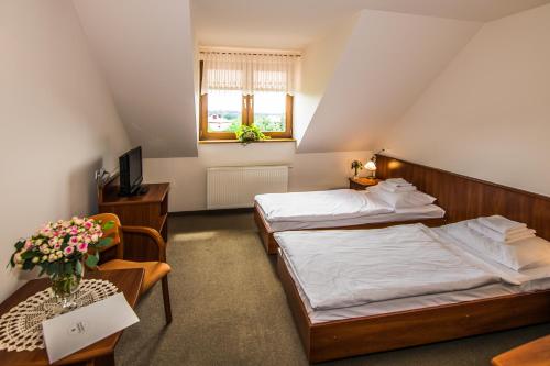 Libiąż的住宿－哥什涅茨納羅茲德洛若汽車旅館，一间卧室配有两张床、一张桌子和一台电视。