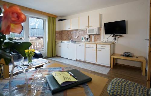 a kitchen with white cabinets and a table at Alpenstern rooms & suites in Lermoos
