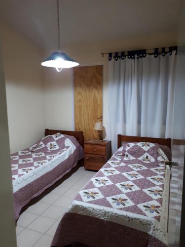 1 dormitorio con 2 camas y mesa con lámpara en Casa Temporaria en San Rafael