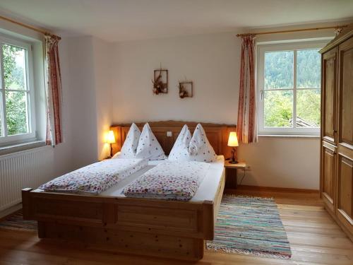a bedroom with a bed with two lamps and two windows at Biobauernhof Schöttelbauer in Rosenau am Hengstpass