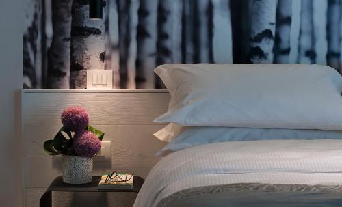 a bedroom with a bed and a table with a clock and flowers at Hotel Locanda Al Piave ***S in San Donà di Piave