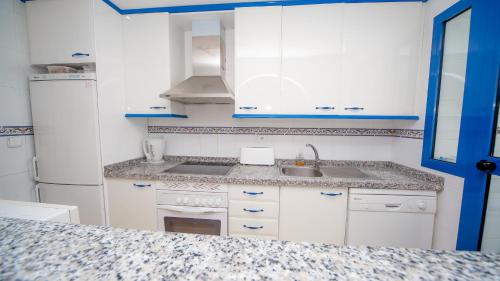 マニルバにあるMykonos Playa 19の白いキャビネット、シンク、冷蔵庫付きのキッチンが備わります。