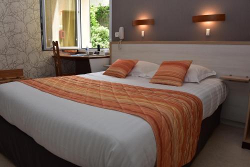 a large bed with orange pillows in a hotel room at Logis Hôtel Bellevue in Bessines-sur-Gartempe