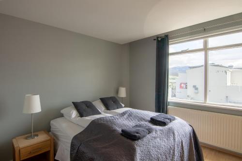 a bedroom with a bed and a large window at Acco Town Square Apartments in Akureyri