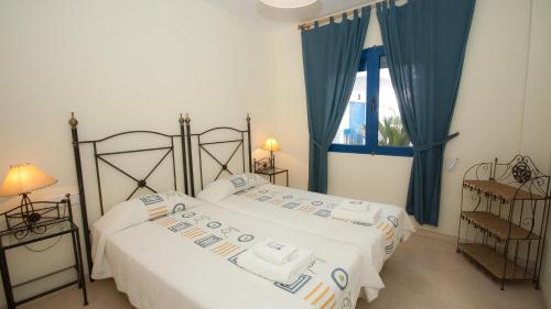 マニルバにあるMykonos Playa 18のベッドルーム1室(青いカーテンと窓付きのベッド2台付)