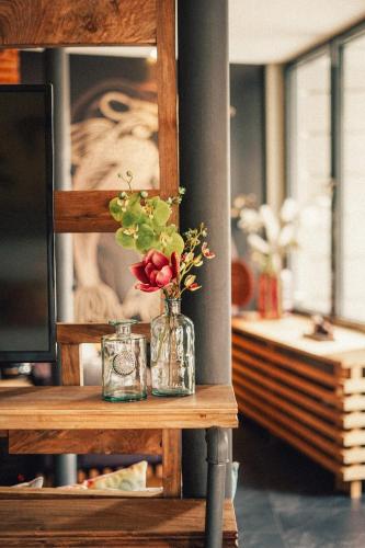 a vase of flowers on a table with a picture at 36 Phô Cô Hotel & Suites in Weimar