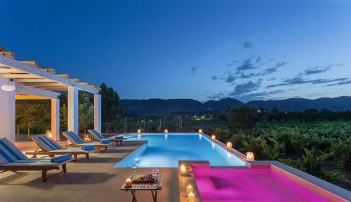 einen Pool im Hinterhof mit Stühlen und einem Tisch in der Unterkunft Aneli Luxury Villas-Villa Elissavet in Áyios Kírikos