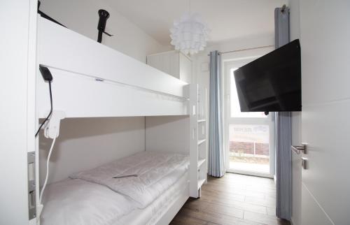 Dieses weiße Zimmer verfügt über ein Etagenbett und einen Flachbild-TV. in der Unterkunft Wohnen am Yachthafen W46 in Cuxhaven