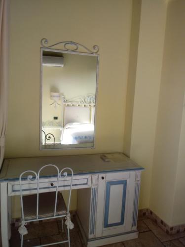 een kaptafel met een spiegel in de kamer bij Hotel Corsaro Nero in Portu Maga