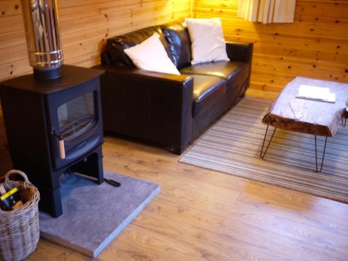 uma sala de estar com um sofá de couro e um fogão a lenha em Dulnain em Aviemore
