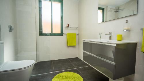 een badkamer met een wastafel, een toilet en een spiegel bij La Almadraba 227 in Manilva