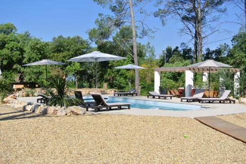 een zwembad met stoelen en parasols naast bij LA MAISON DES "BOIS" in Lorgues