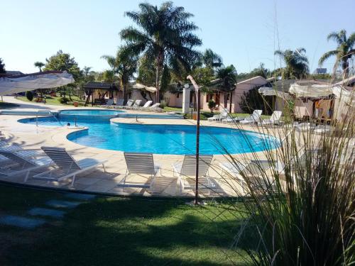 a large swimming pool with chairs and palm trees at Arapey Oasis Termal Hotel in Termas del Arapey
