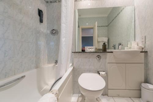 a white bathroom with a toilet and a sink at Alexandra Hotel in Fort William