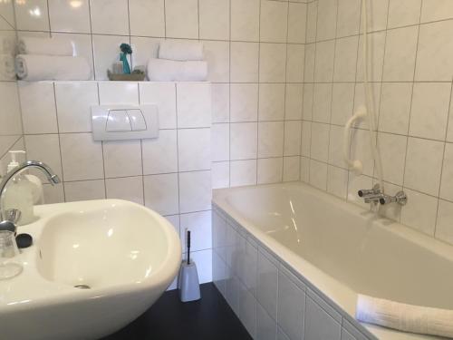Baño blanco con bañera y lavamanos en Hotel Eetcafé 't Dûke Lûk en Veenwoudsterwal