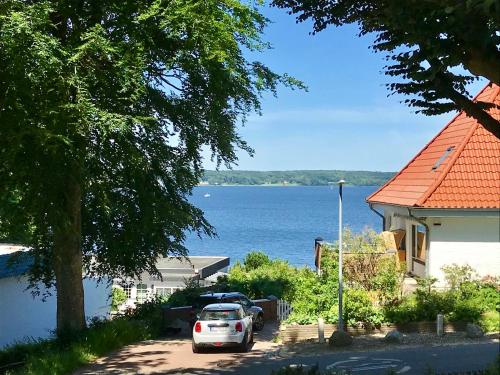 a car parked in front of a house next to the water at Ferienwohnung in Sandwig in Glücksburg