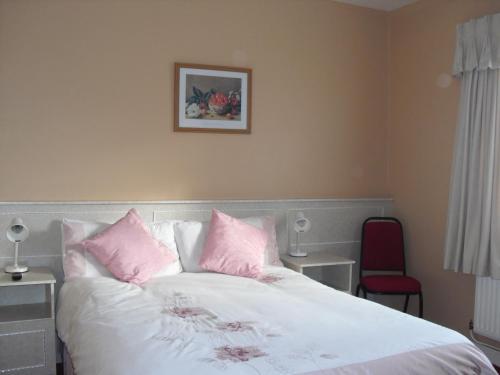 BeaufortにあるThe Purple Heather B&Bのベッドルーム(ピンクの枕が付いた白いベッド付)