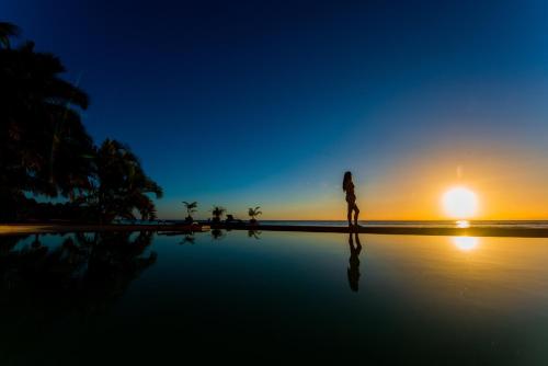 a woman walking on the beach at sunset at Hotel Vanivola & SPA in Sainte Marie