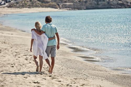 a man and a woman walking on the beach at Archipelagos Hotel - Small Luxury Hotels of the World in Kalo Livadi