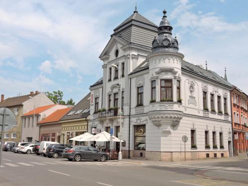 um edifício branco com uma torre numa rua em Olymp penzion em Komárno