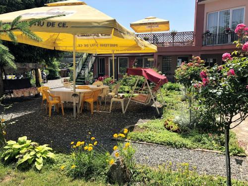 a table and chairs under an umbrella in a garden at Casa Constantin si Elena ( Adults only ) in Eforie Nord