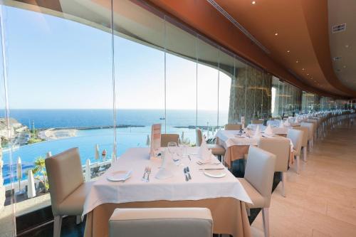 a restaurant with tables and chairs with a view of the ocean at Gloria Palace Royal Hotel & Spa in Puerto Rico de Gran Canaria