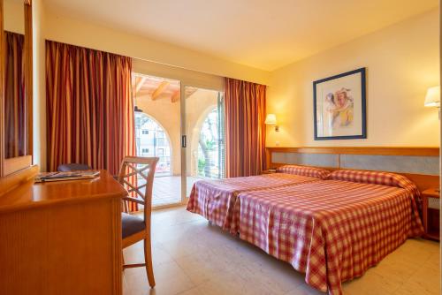 a hotel room with a bed and a desk and a window at Paz y Mar, Santa Ponsa in Santa Ponsa
