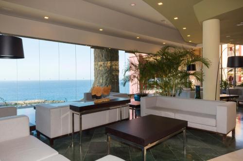 a lobby with white furniture and a view of the ocean at Gloria Palace Royal Hotel & Spa in Puerto Rico de Gran Canaria