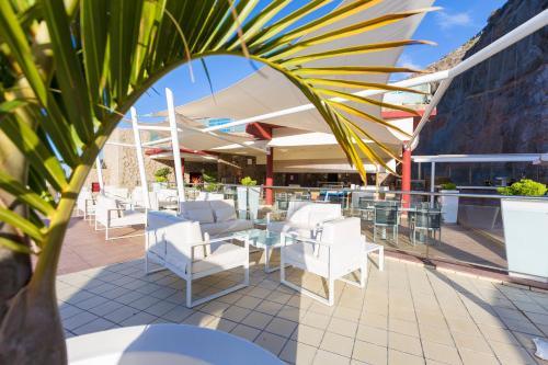 
a patio area with chairs, tables and umbrellas at Gloria Palace Royal Hotel & Spa in Puerto Rico de Gran Canaria
