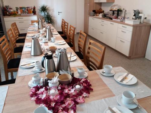a long table with plates and utensils on it at Gästehaus Am Hochsimmer in Ettringen