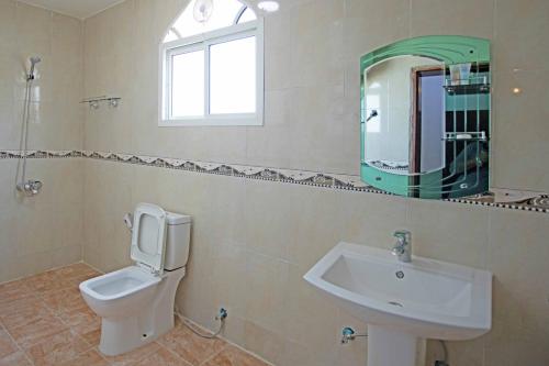 y baño con lavabo, aseo y espejo. en Star Emirates Furnished Apartments 2, en Salalah