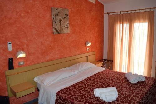 una camera d'albergo con un letto con pareti rosse di Hotel Ottavia a Rimini