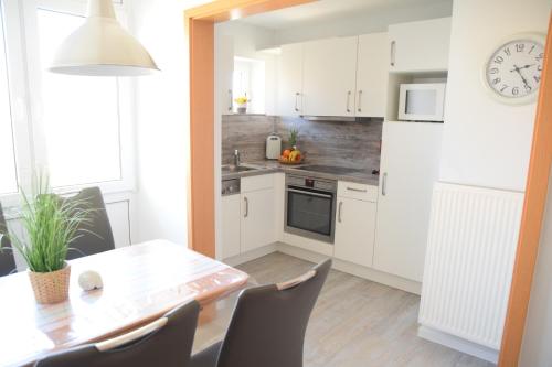 a kitchen with white cabinets and a table with chairs at Hotel Thode in Dahme