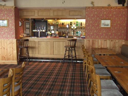 ein Restaurant mit Holztischen und -stühlen und einer Bar in der Unterkunft Grosvenor Hotel in Robin Hood's Bay