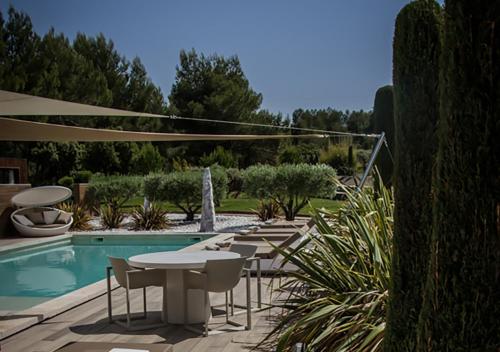 a patio with tables and chairs next to a swimming pool at Mas des Cigales in Eygalières