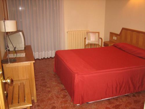 a hotel room with a red bed and a television at Hotel Chané in Puebla de Alfindén