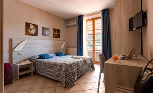 a bedroom with a bed and a desk with a laptop at Hotel Corallo in Pomonte