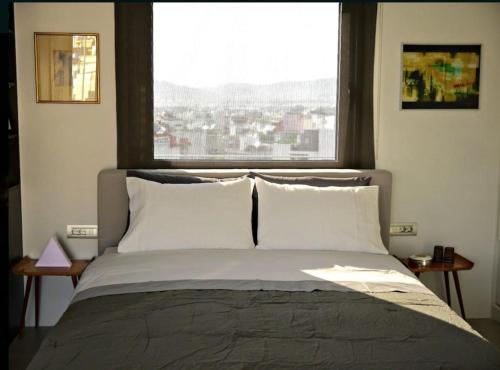 a bed in a bedroom with a large window at Stylish penthouse with Acropolis and 360 view in Athens